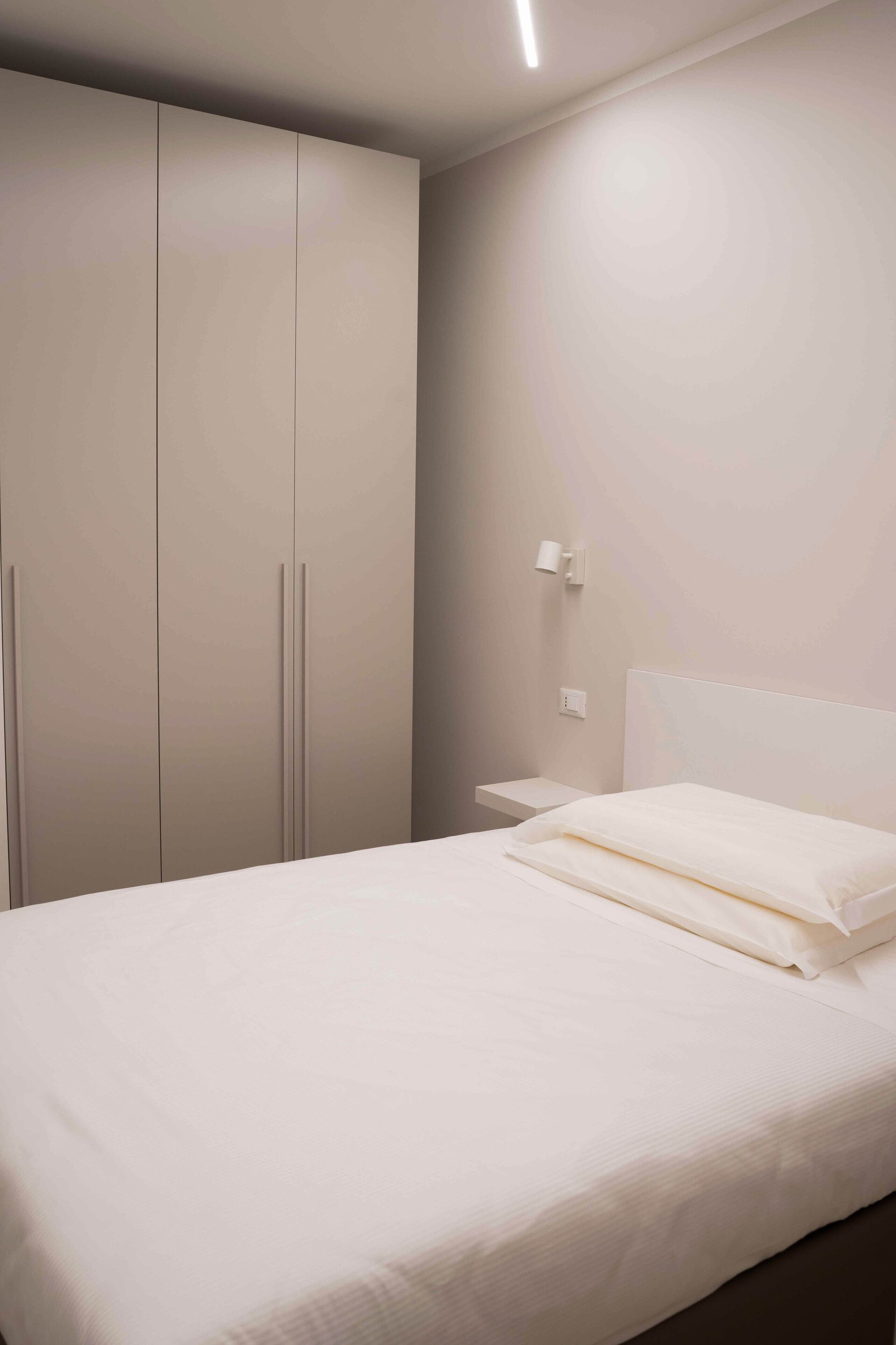 A bedroom with a bed, a wardrobe, and a nightstand.