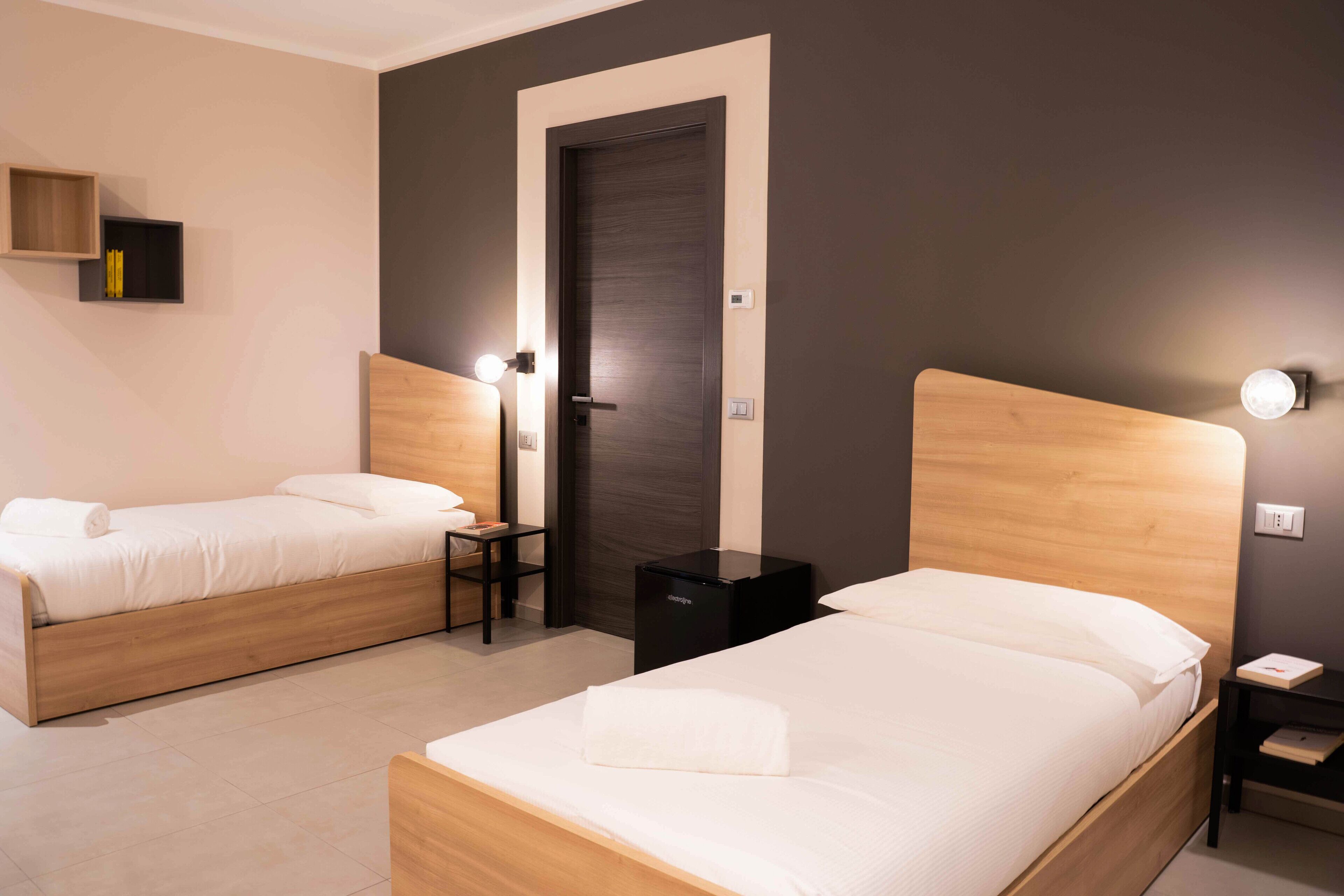 Two single beds with wooden headboards, a small table, and a black nightstand with a lamp.