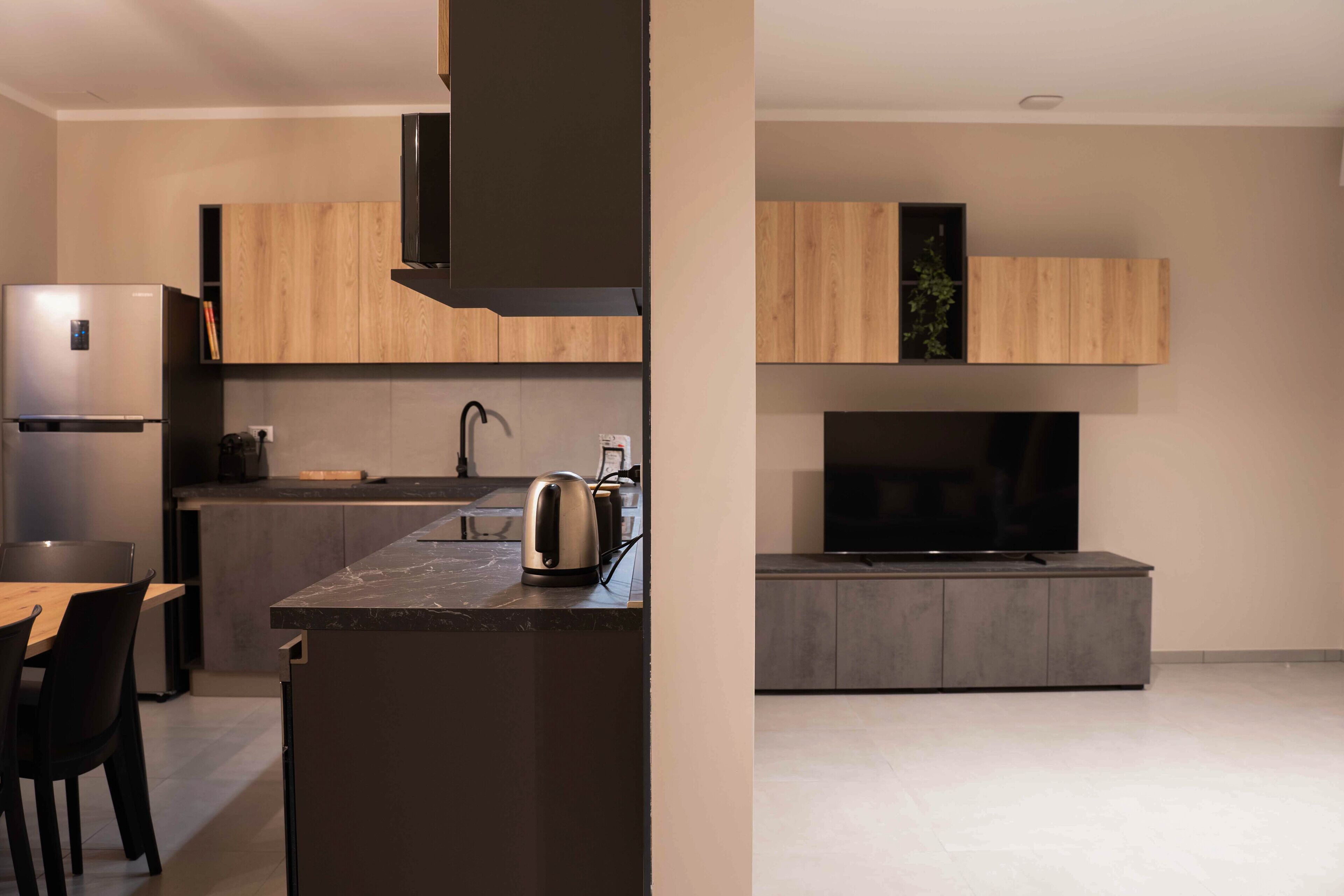 A modern kitchen with a built-in oven, a coffee maker, and a flat-screen TV.