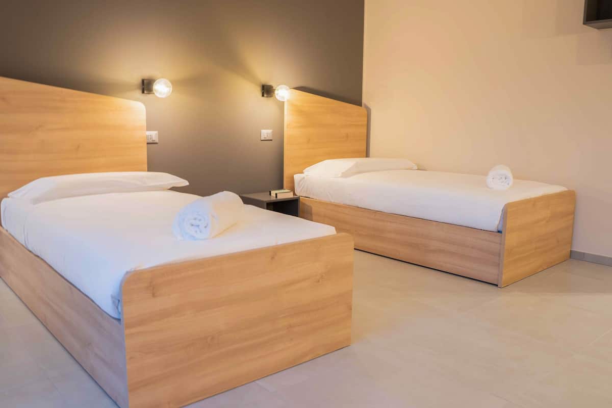Two wooden beds with white bedding and a nightstand between them.