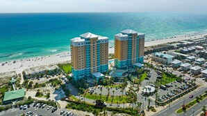 Un hotel costero con dos edificios destacados, una playa y un estacionamiento.