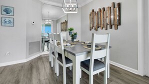 Un comedor con una mesa rectangular, sillas blancas y una lámpara colgante.
