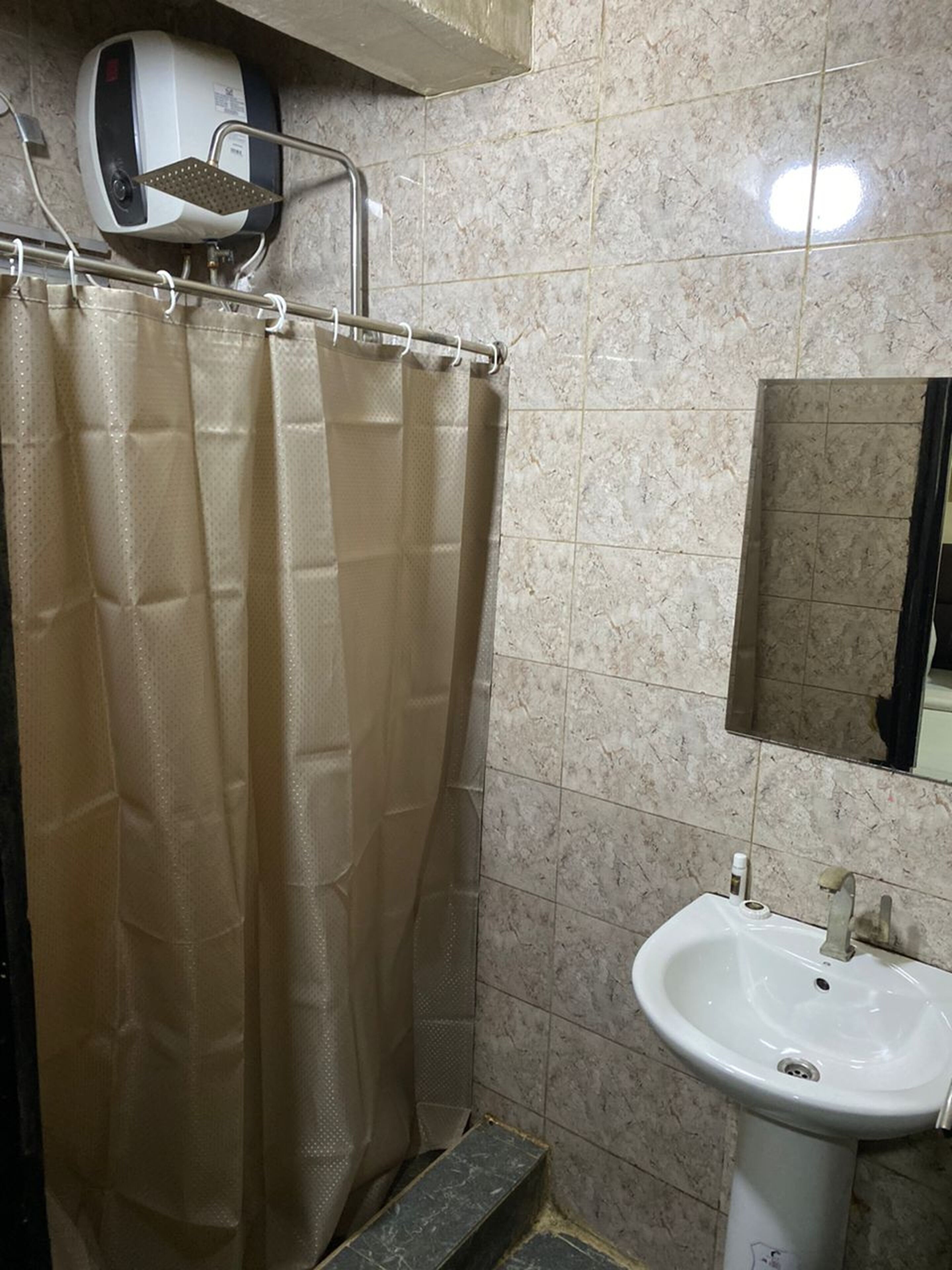 A bathroom with a shower curtain, a sink, and a mirror.