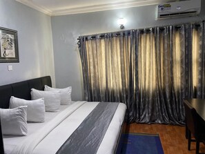 A hotel room with a bed, a desk, and an air conditioning unit. - Kilo Royal Hotel (Lagos)