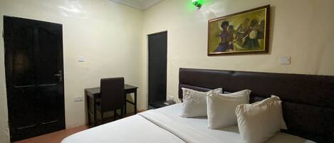 A hotel room with a bed, a desk, and a chair.