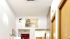 A hotel lobby with a red leather sofa, a wooden reception desk, and a hallway leading to doors. - Hotel Domus Termini (Rome)