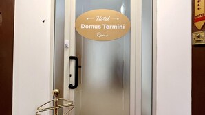 A hotel entrance with a frosted glass door, a red carpet, and a sign indicating 'Hotel Domus Termini Rome'. - Hotel Domus Termini (Rome)