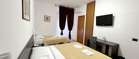 Habitación de hotel con dos camas, un escritorio, una silla, un televisor y una ventana con cortinas.
