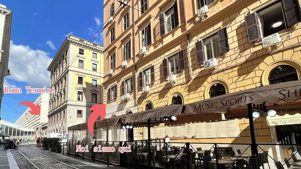 A street view with a tram line, buildings with shops, and a sign reading "Roma Termini". - Hotel Domus Termini (Rome)