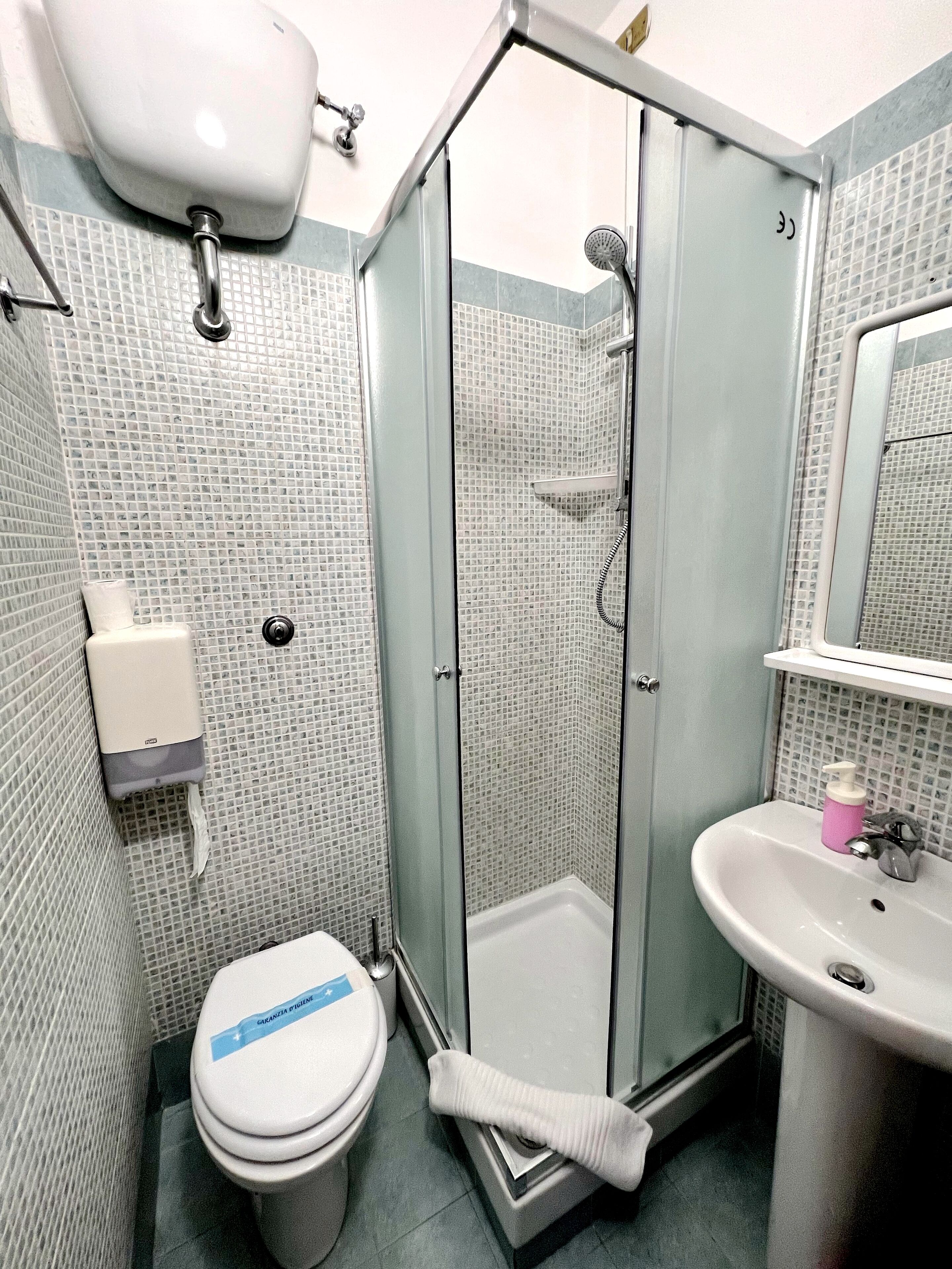 A bathroom with a glass-enclosed shower, a toilet, and a sink.