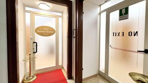 A hotel entrance with a red carpet, a sign for 'Domus Termini Rome', and an emergency exit sign. - Hotel Domus Termini (Rome)