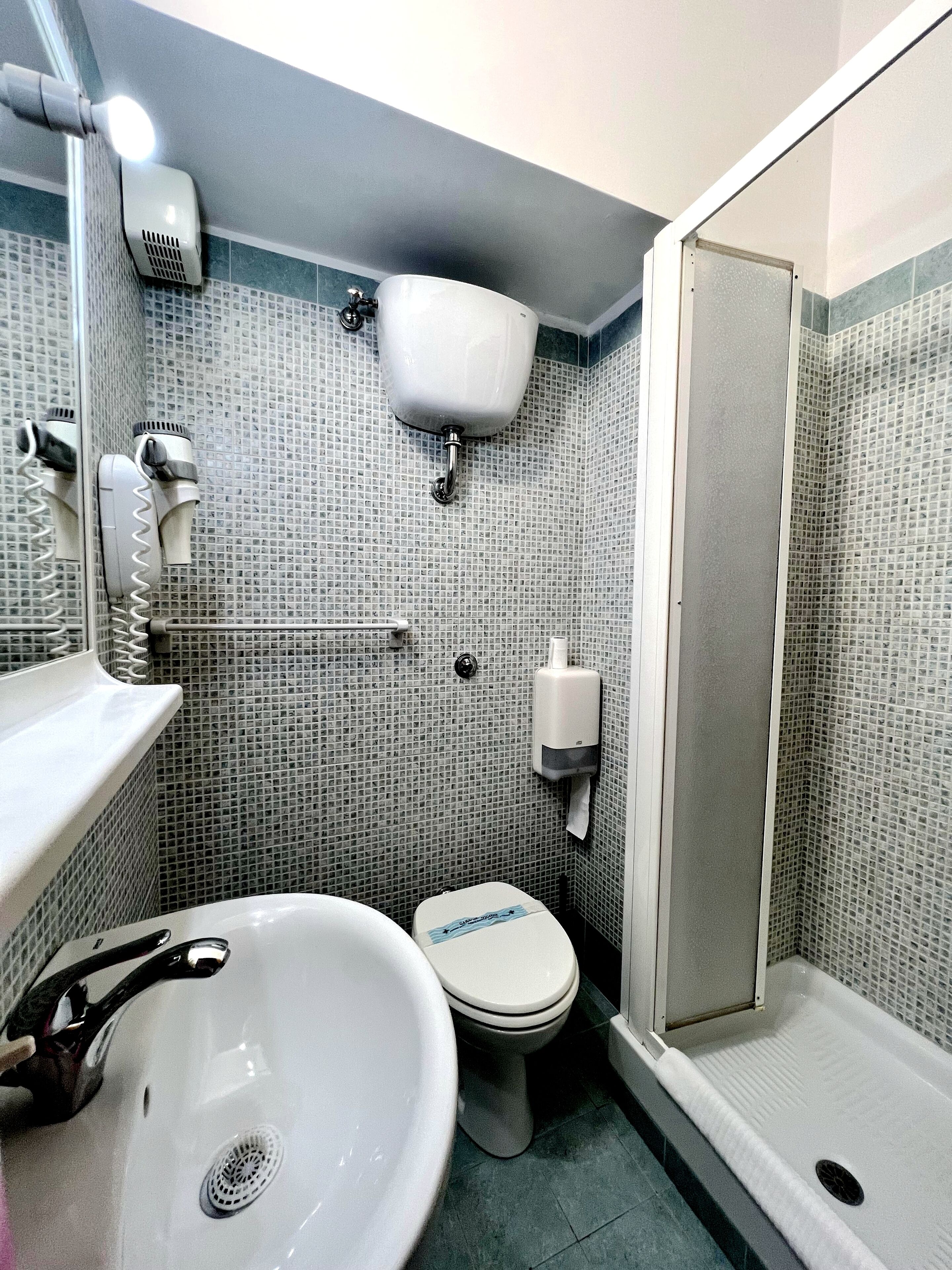 A bathroom with a white sink, toilet, and a shower area.