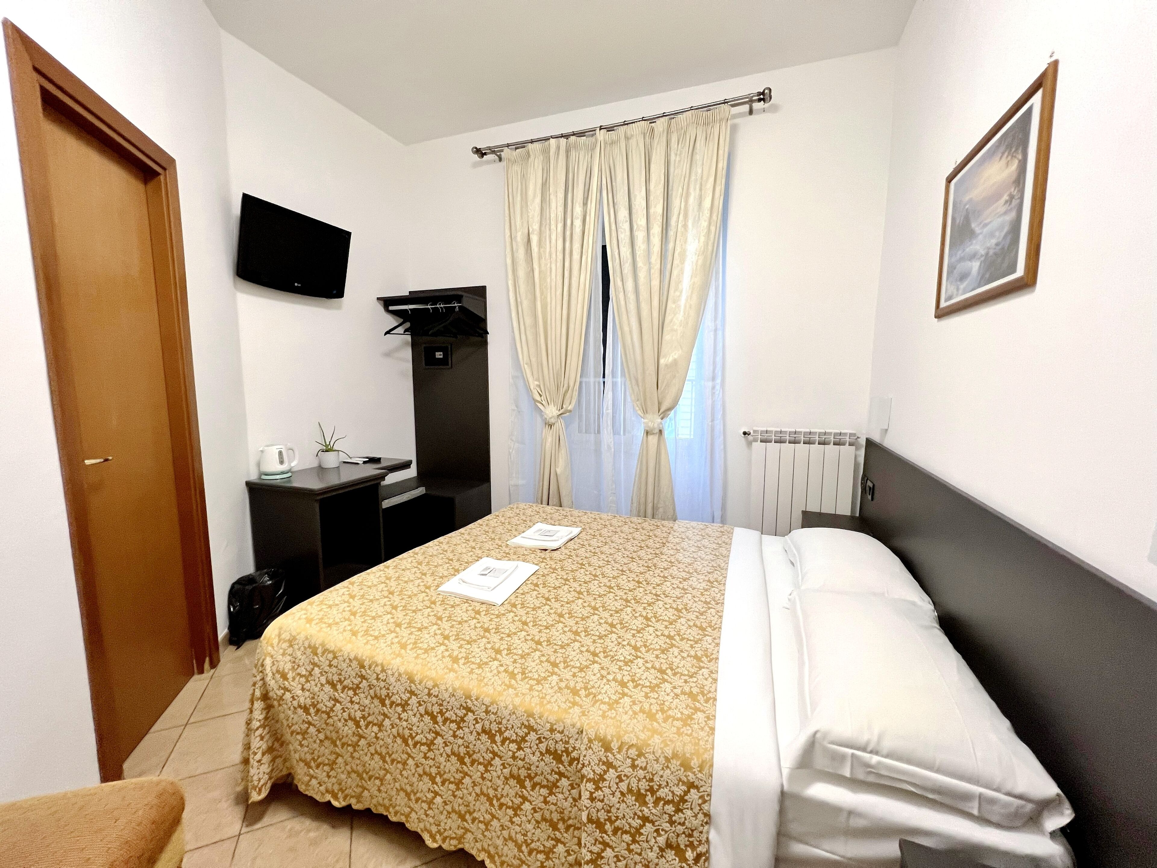 Ein Schlafzimmer mit einem Bett, einem Schreibtisch, einem Sessel, einem Fernseher und einer Heizung.