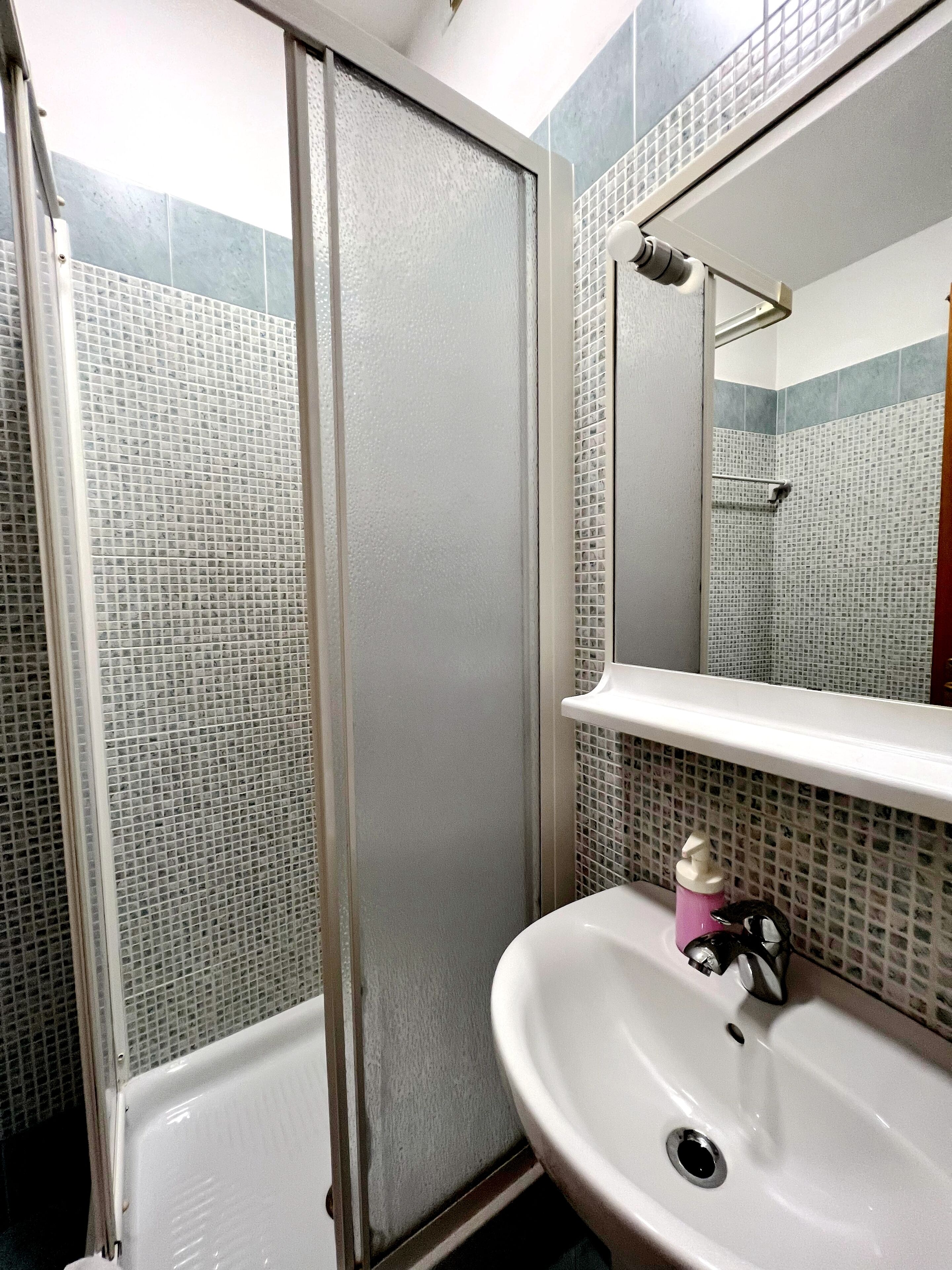 A bathroom with a shower, a sink, and a mirror.