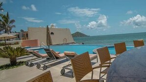 Un área junto a la piscina con sillones de descanso y vistas al océano.