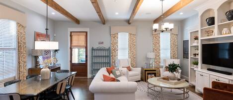 A spacious living area with a dining table, sofa, and TV.