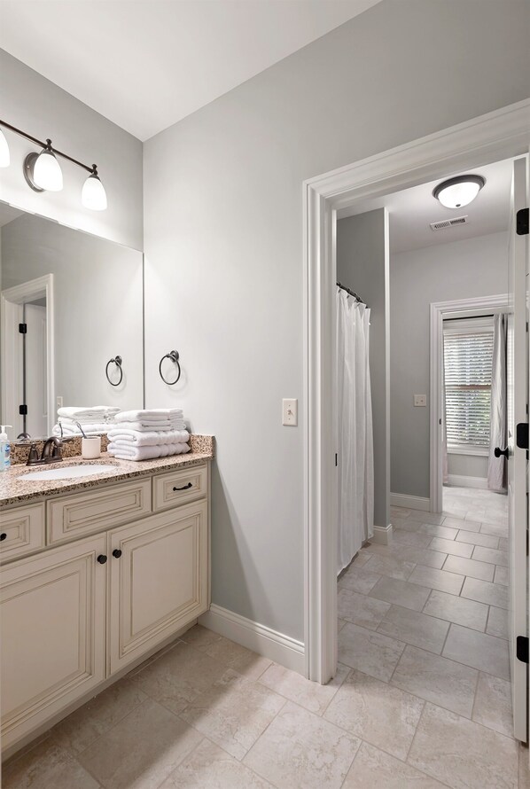 A bathroom with a vanity, a mirror, and a shower curtain.