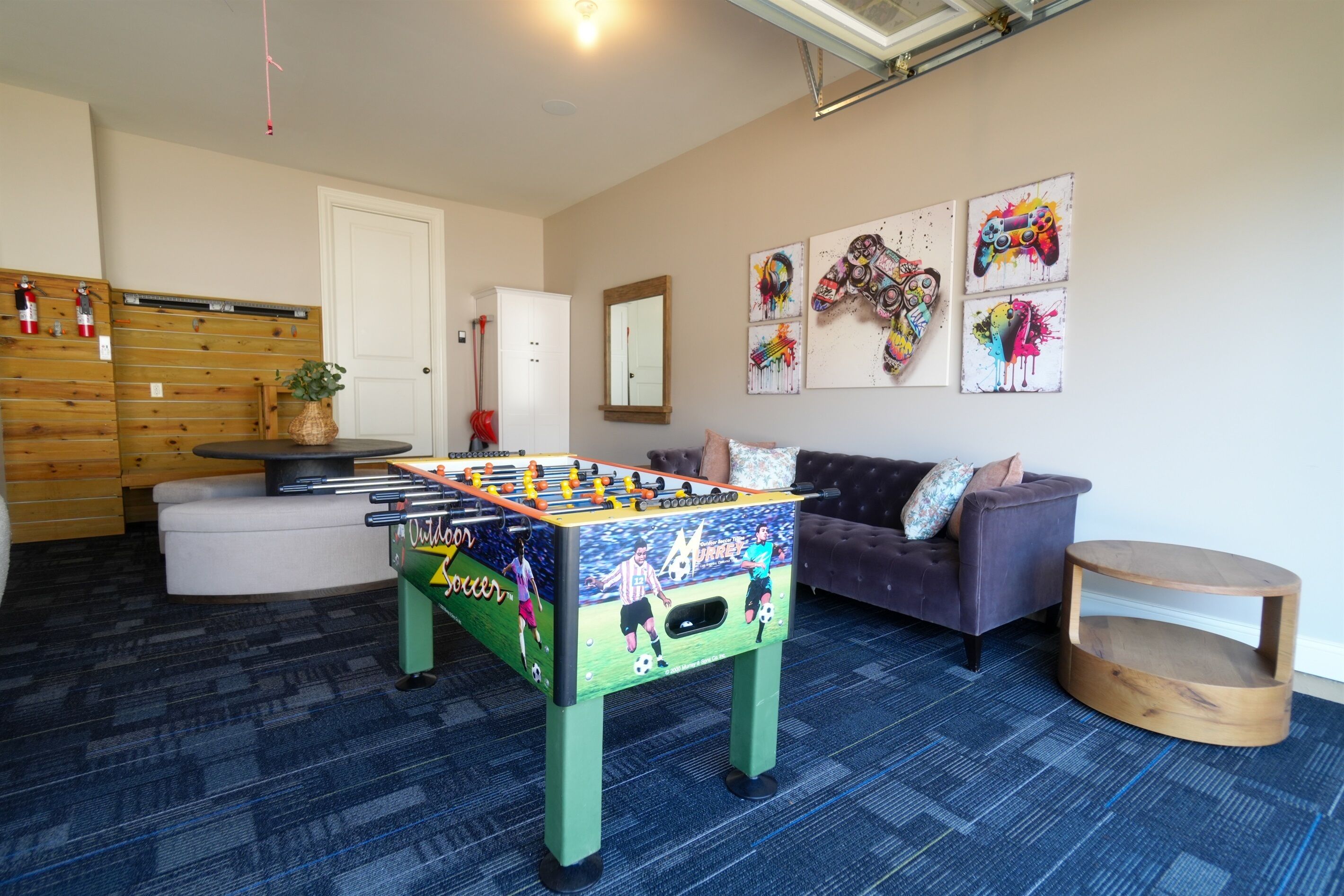 A room with a foosball table, a sofa, a coffee table, and wall art.