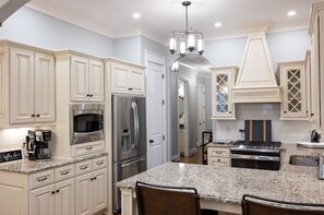 A modern kitchen with white cabinetry, stainless steel appliances, and a granite countertop.
