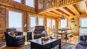 A cozy log cabin interior with a dining area, two sofas, and a coffee table.