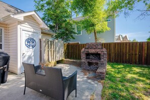 Un jardin avec une cheminée en briques, une chaise de patio et une clôture en bois.