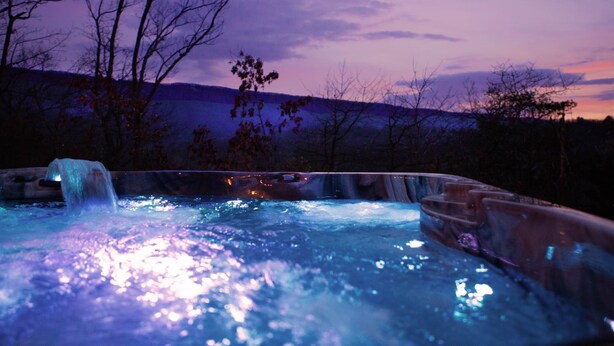 Ein Whirlpool mit Blick auf eine gebirgige Landschaft im Abenddämmerung.