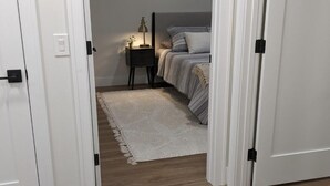 Quarto com cama, mesa de cabeceira, abajur e tapete.