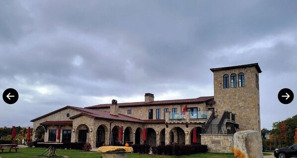 A stone building with a tower, arched windows, and a staircase leading to a balcony.