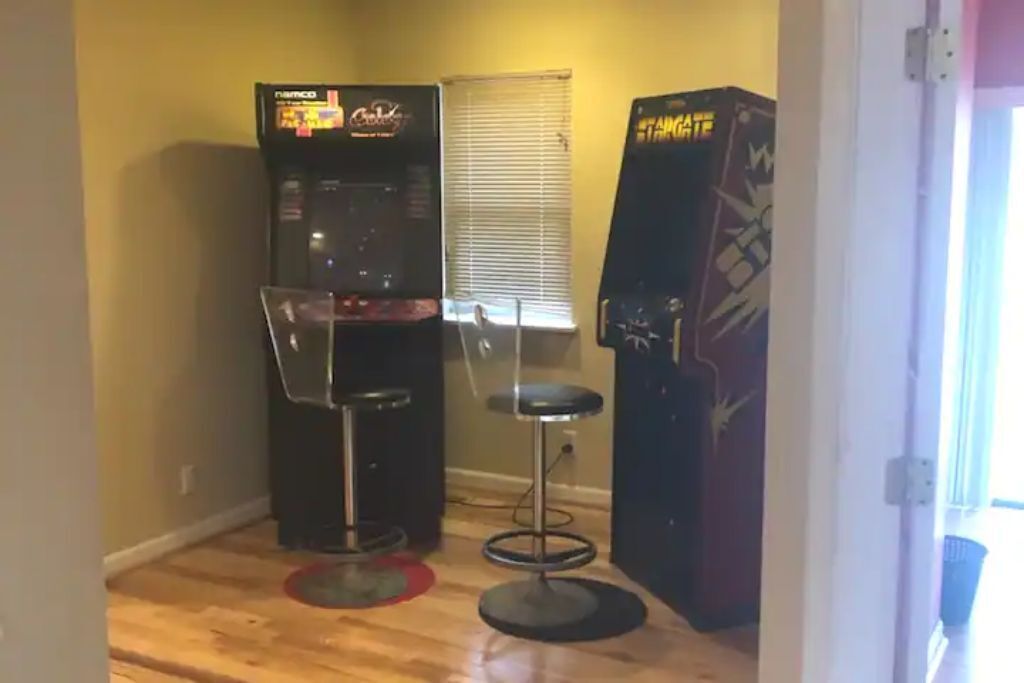 A room with a wooden floor, a vending machine, a small stool, and a poster on the wall.