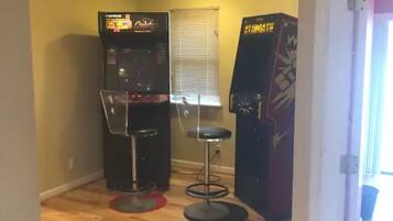 A room with a wooden floor, a vending machine, a small stool, and a poster on the wall.