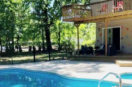 A pool area with a wooden deck and a fenced enclosure.