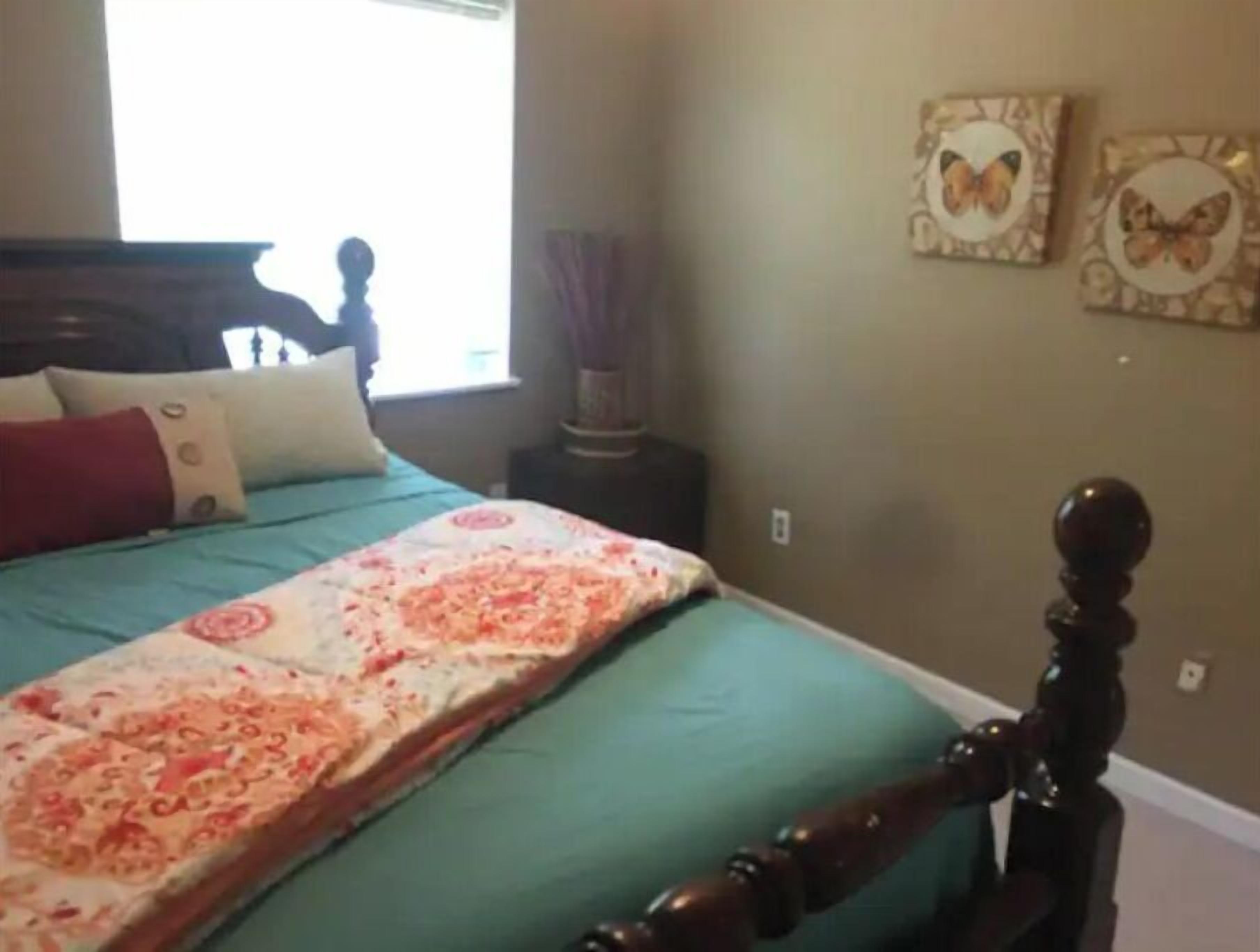 A bedroom with a bed, a nightstand, a window, and wall decorations.
