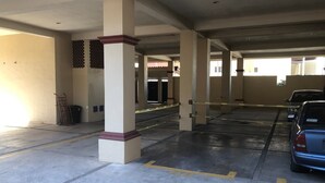 A parking garage with concrete pillars, yellow parking lines, and caution tape. - Departamentos MDR (Mazatlán)