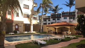 A pool area with lounge chairs and a covered patio. - Departamentos MDR (Mazatlán)