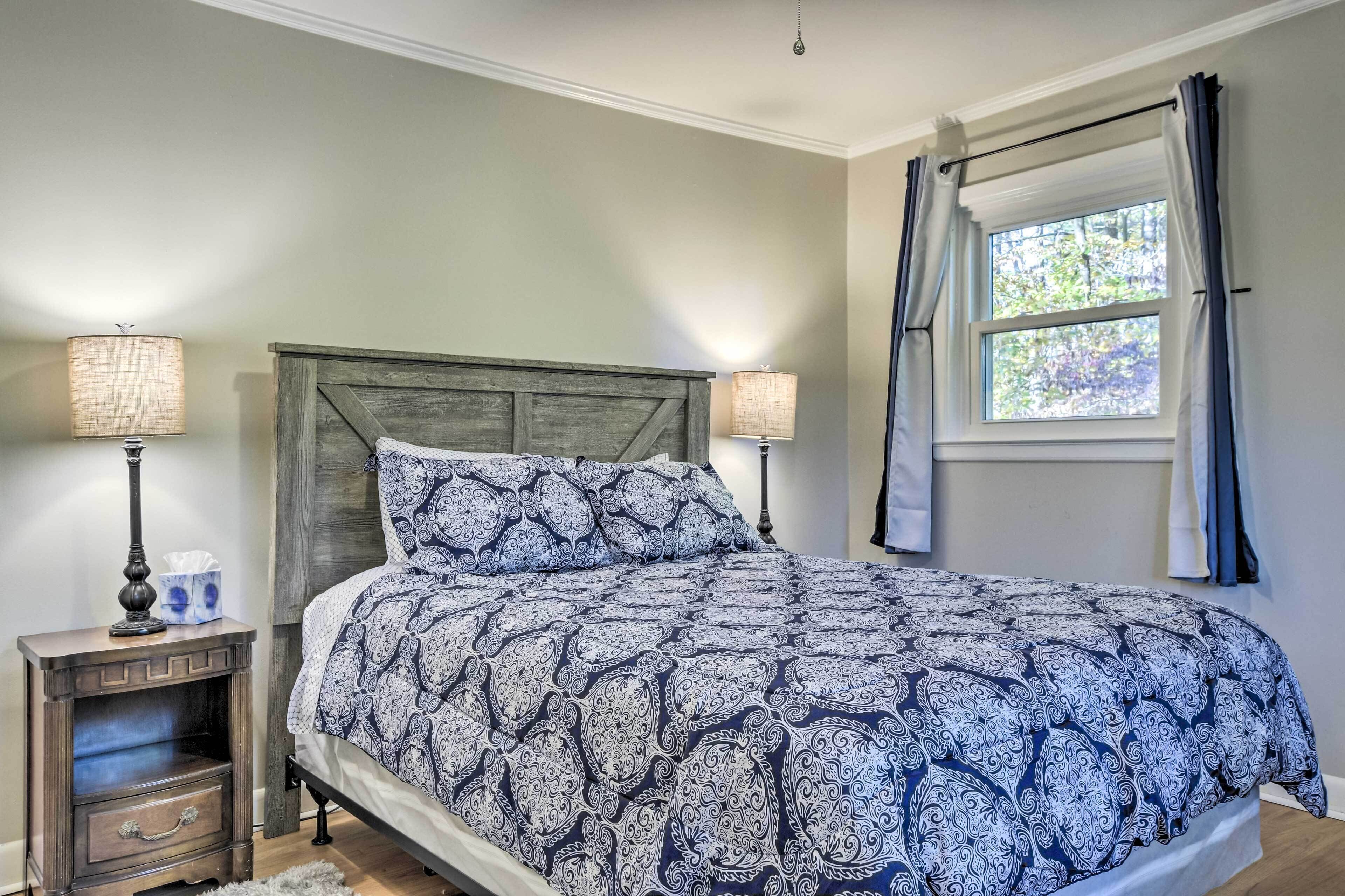 Quarto com uma cama, duas mesas de cabeceira, uma janela com cortinas e uma luminária em cada mesa.