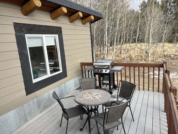 A deck with a grill, a table, and chairs.