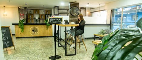 A modern interior with a reception desk, a laptop on a table, and a large clock on the wall.