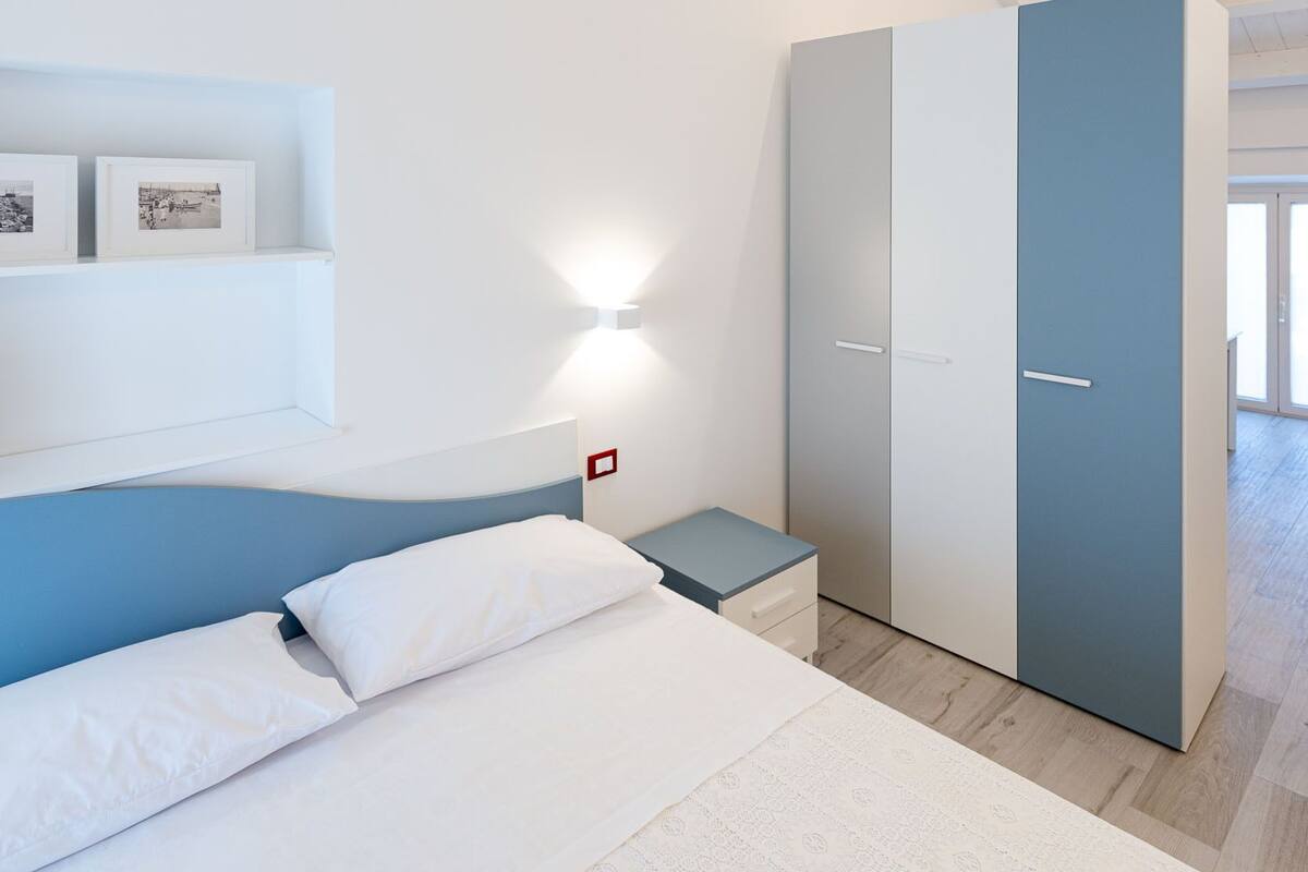 Une chambre à coucher comprenant un lit, une table de chevet, une armoire et une lampe fixée au mur.