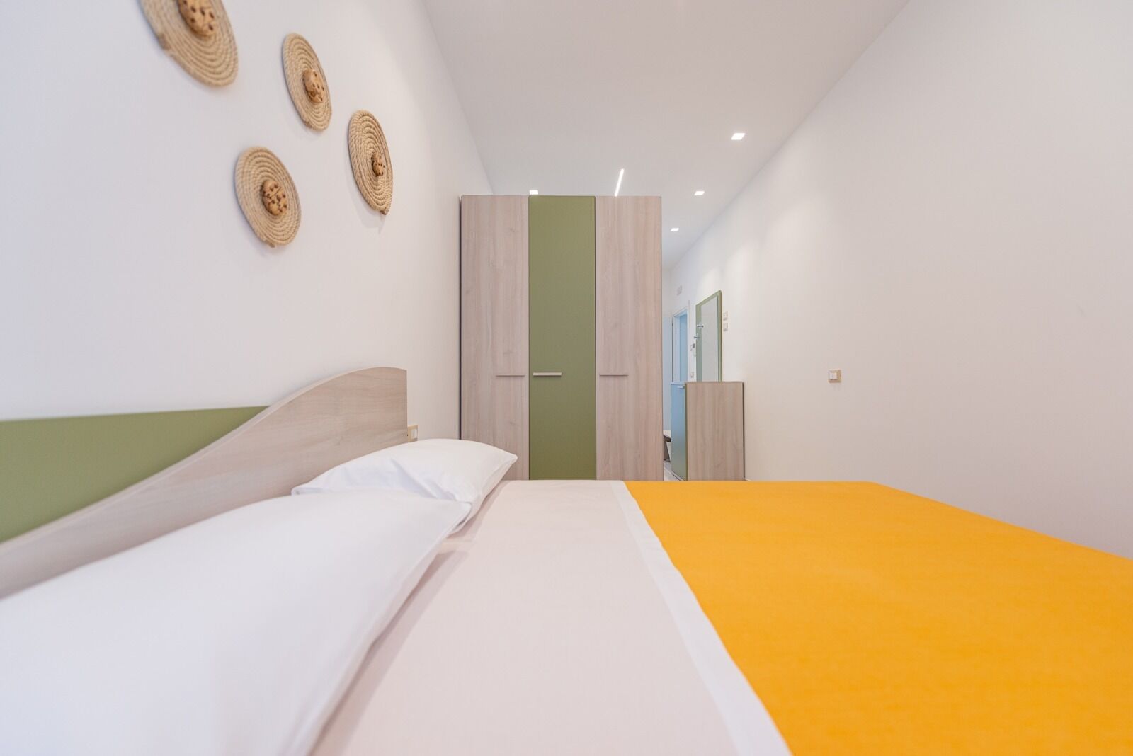 Une chambre à coucher moderne avec un lit, une armoire et un miroir.