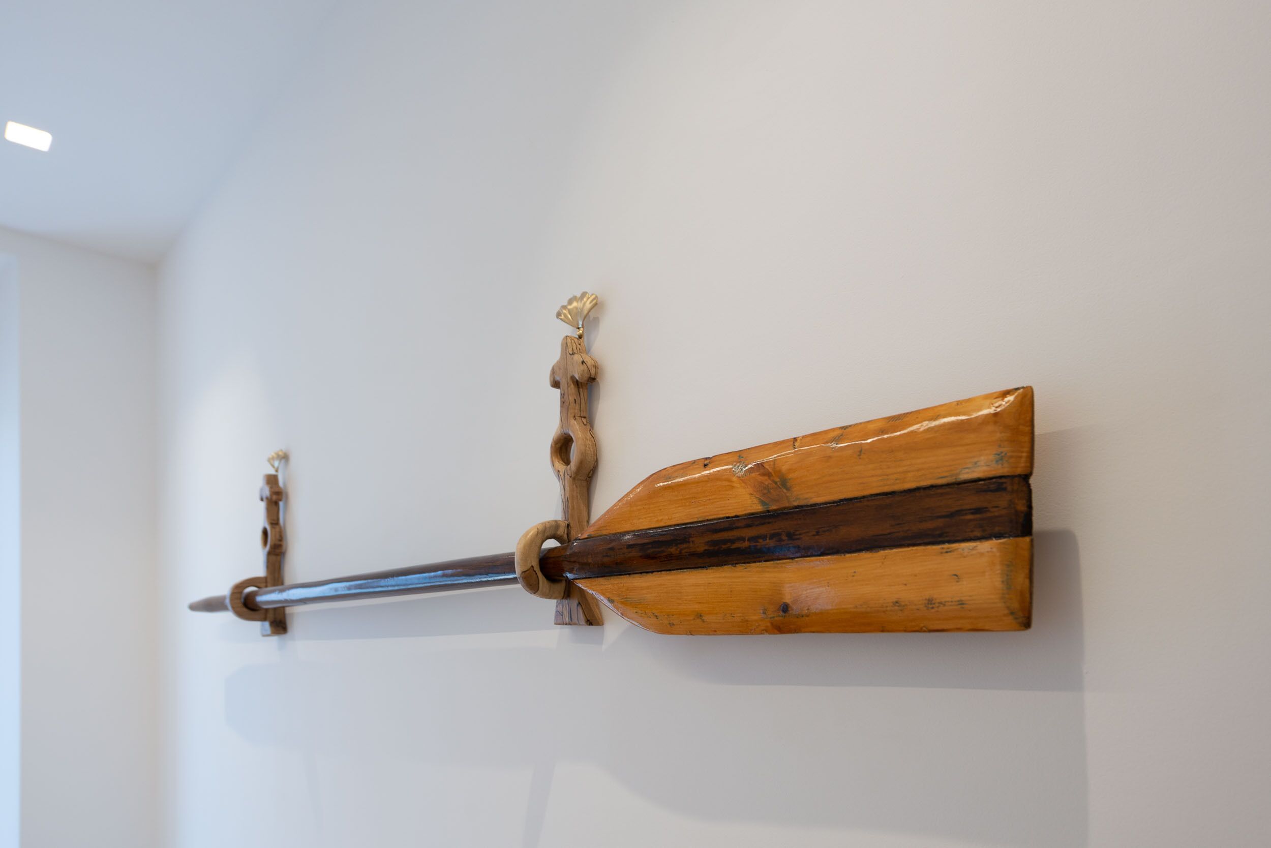 Un objet en bois fixé au mur, muni d’une tige en métal et d’un manche en bois.