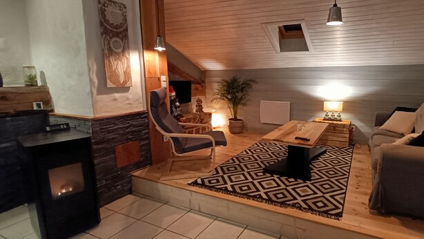 Ein gemütliches Wohnzimmer mit Kamin, einer Couch, einem Couchtisch und einem gemusterten Teppich.