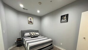 Een slaapkamer met een bed, grijze wanden en een deur.