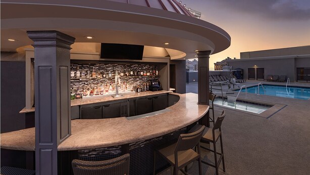 A bar area with a poolside view, including a bar counter, seating, and a pool. - 1BR Villa Walk to Las Vegas Strip - Marriott Grand Chateau - Full Kitchen + Pool (Las Vegas)