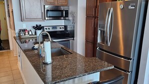 Una cocina moderna con encimeras de granito, electrodomésticos de acero inoxidable y una zona de bar con taburetes.