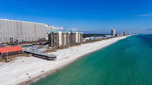 Un hotel costero con varios edificios altos, una playa y aguas turquesas cristalinas.