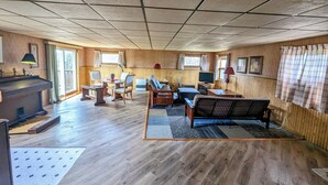 A spacious living room with a piano, a sofa, a TV, and a fireplace. - Dog-Friendly large rural Estate just outside Alex Bay with hot tub and pool! (Alexandria Bay)