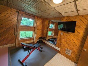 A gym with wooden walls, a TV, and exercise equipment.