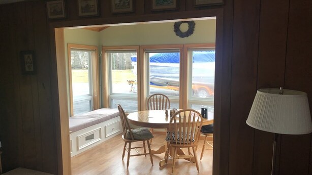 A dining area with a table and chairs, a bench, and a view of a vehicle outside. - Dog-Friendly large rural Estate just outside Alex Bay with hot tub and pool! (Alexandria Bay)