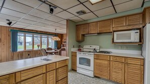 A kitchen with wooden cabinets, a white stove, and a microwave. - Dog-Friendly large rural Estate just outside Alex Bay with hot tub and pool! (Alexandria Bay)