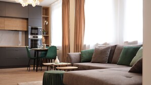 A modern living room with a sectional sofa, a dining area with a table and chairs, and a kitchen with cabinets and appliances.